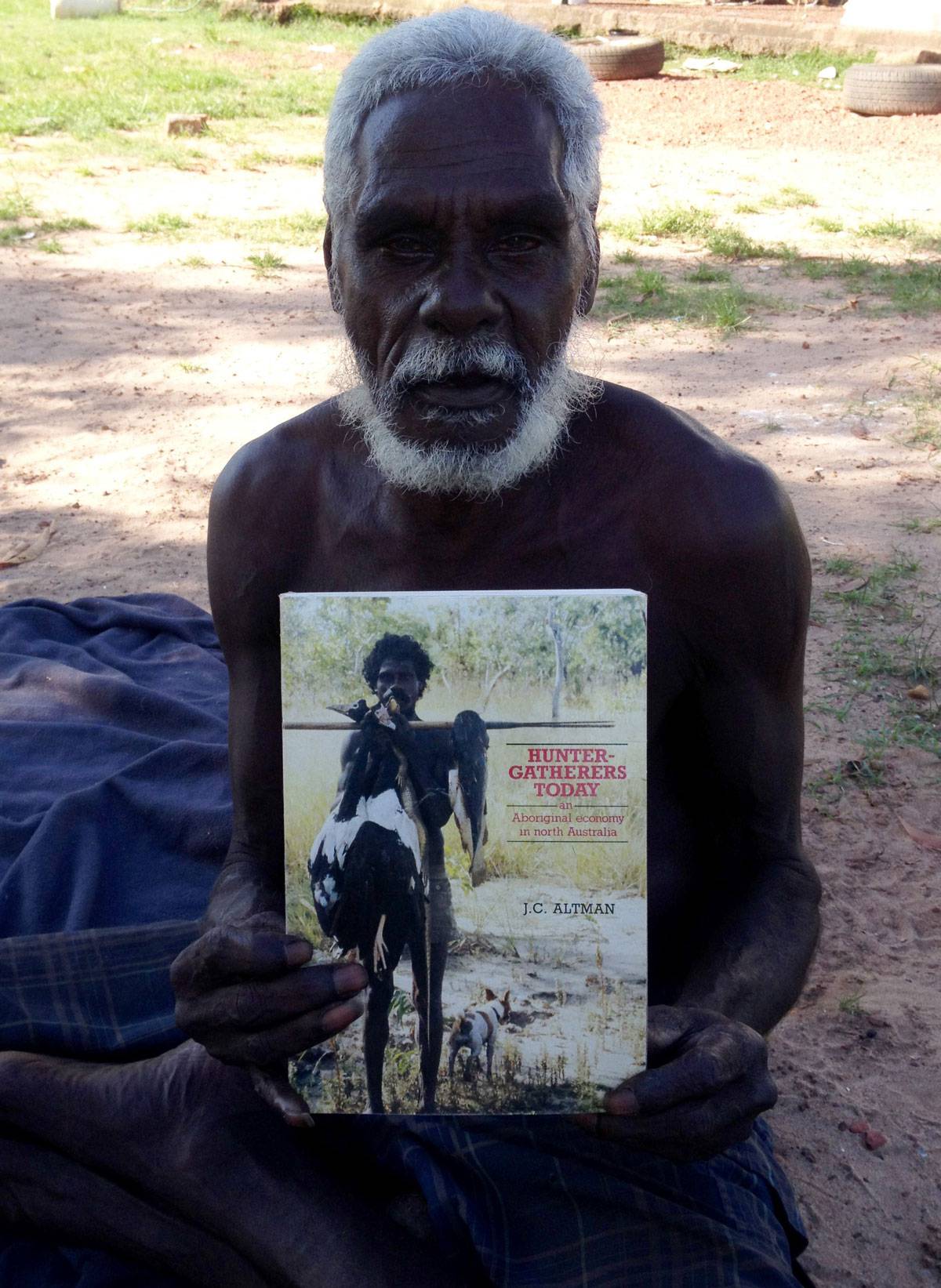 Mawurndjul holds Jon Altman’s book Hunter-Gatherers today
