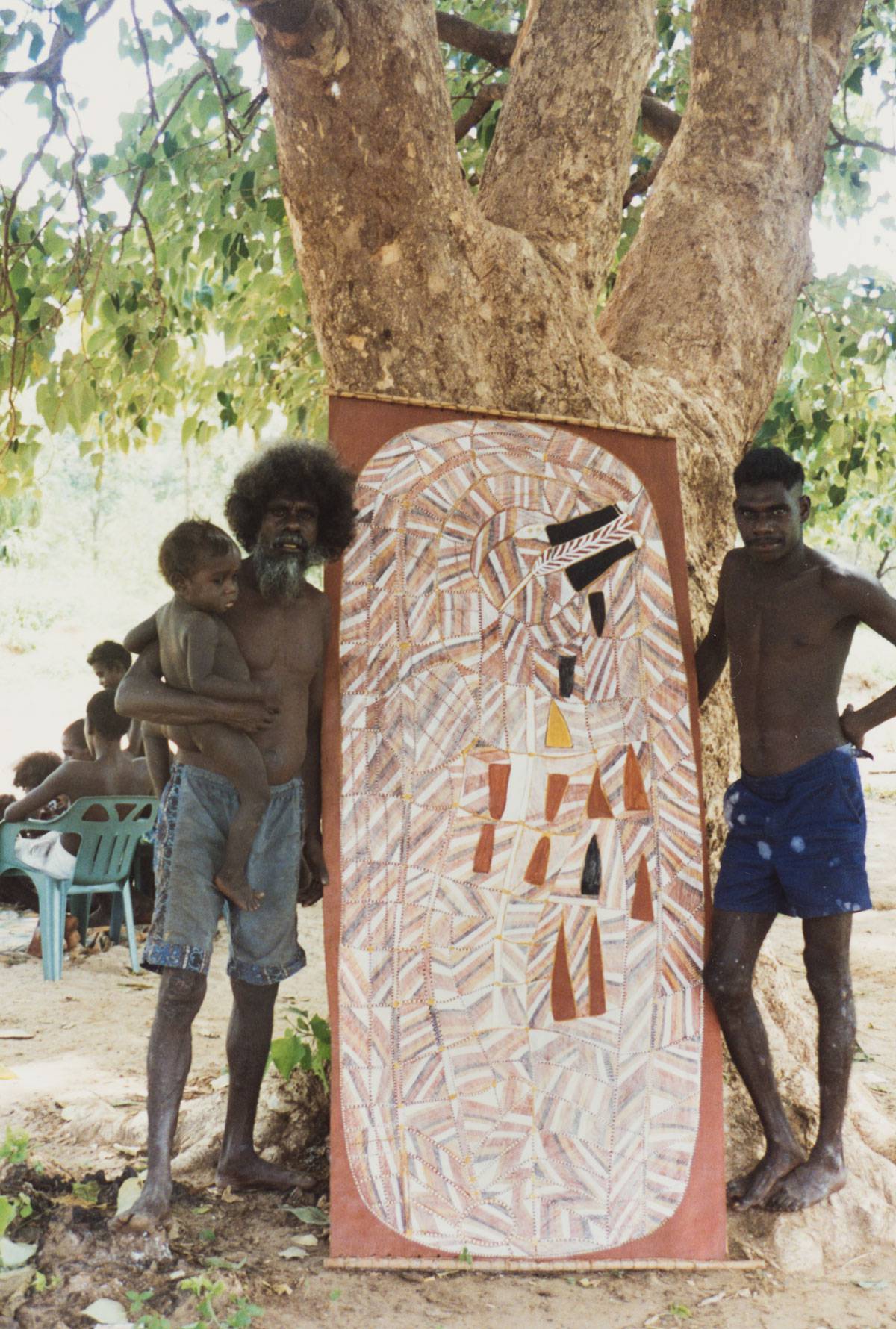 John Mawurndjul and Daniel Mambirri stand together with painting by Mawurndjul